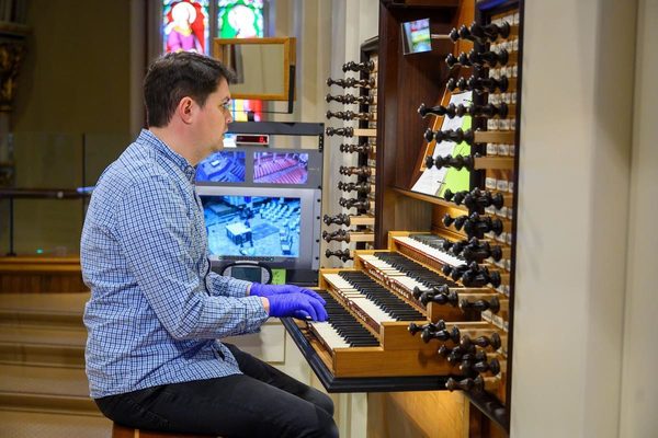 Person Playing The Organ While Wearing Gloves For A Live Streamed Mass